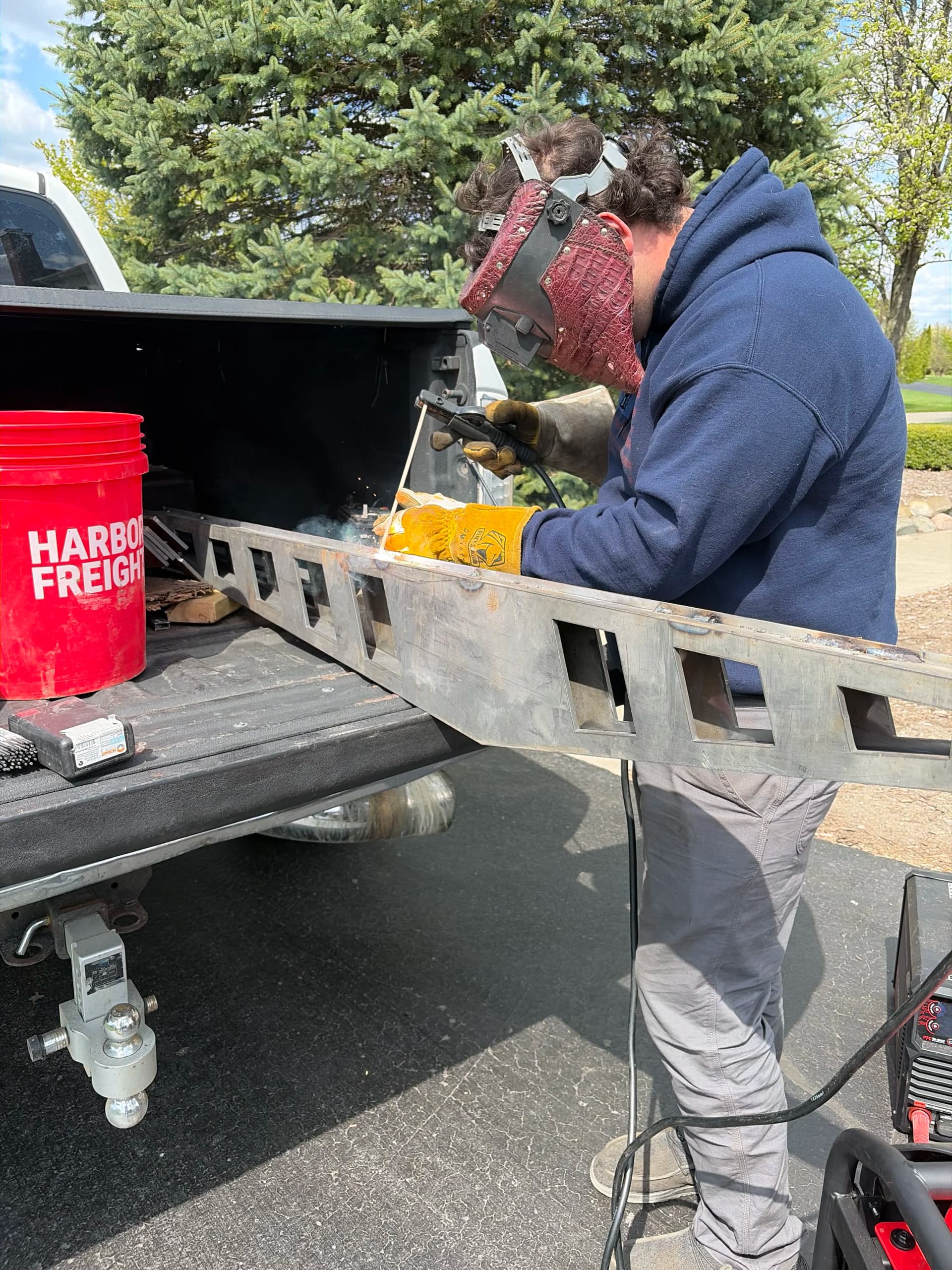 Welder fabricating a long laser-cut steel traction bar for a third-generation Ram