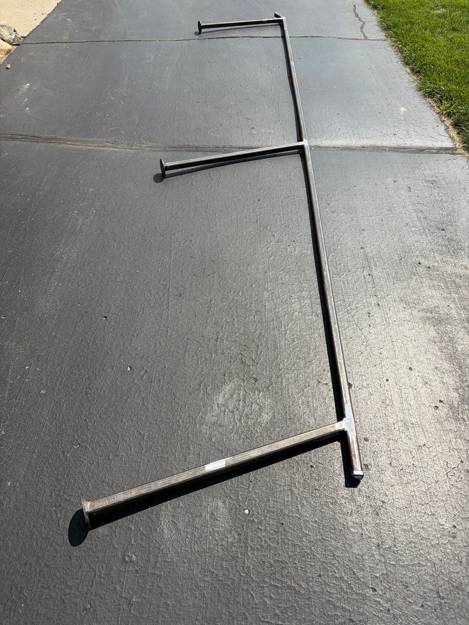 Fabricated steel handrail assembly in bare mill finish, laid out on pavement before powder coating