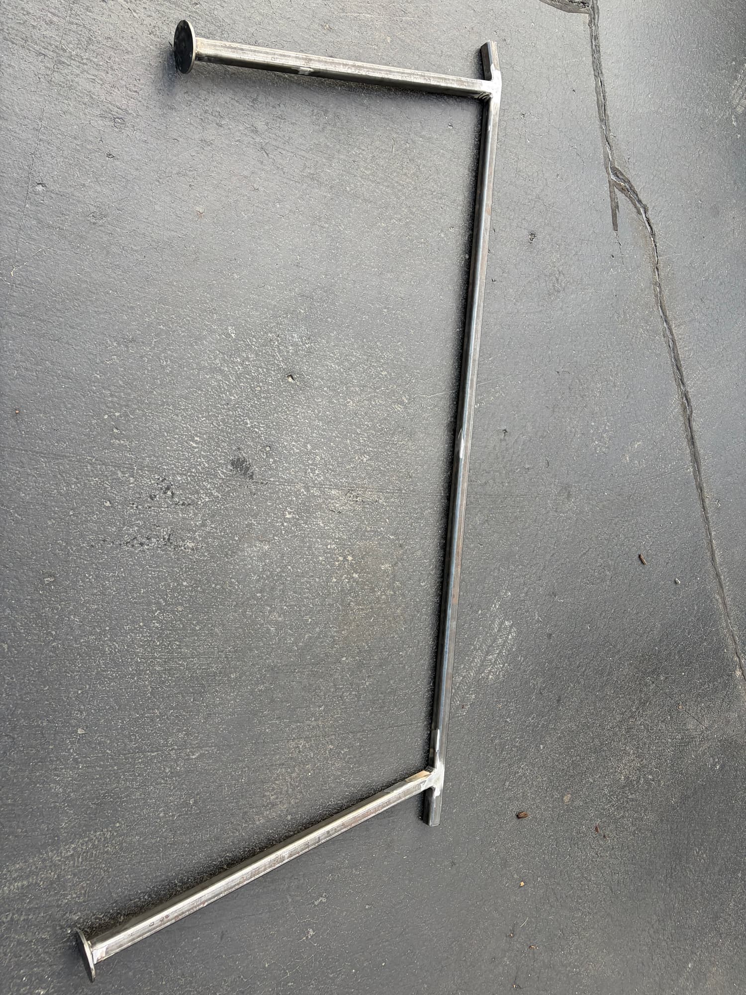 Fabricated steel handrail frame in bare steel with round base plates at each post, before finishing