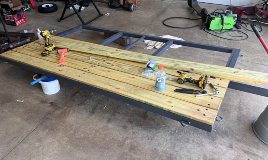 Welded utility-trailer frame with treated wood decking being installed